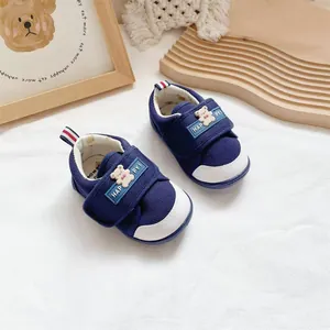 Close-up detail of navy blue baby walking shoes with cute bear patches and Velcro straps