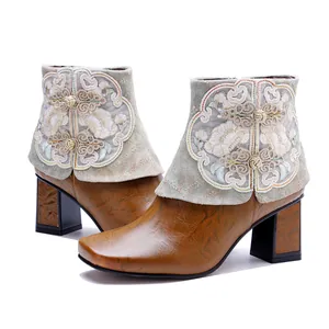 Detailed view of handmade ethnic boots with floral embroidery and rubbed leather texture