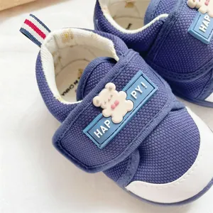 Detailed view of navy blue baby walker shoes featuring a cute cartoon bear and velcro strap