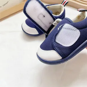 Close-up of navy blue mesh baby walking shoes with a large white velcro strap detail