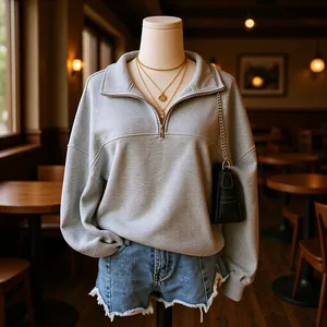 Detailansicht eines grauen Sweatshirts mit halbem Reißverschluss und Goldketten