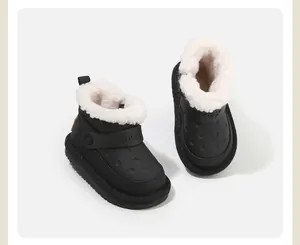 Macro view of black kids snow boots featuring soft white faux fur lining and strap.