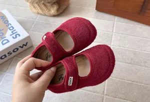 Primo piano dettagliato della morbida texture in feltro bordeaux di scarpe bimba retrò