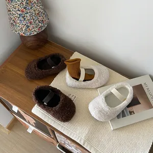 Chaussures d'hiver douillettes en peluche pour filles, marron et crème, sur un tapis.
