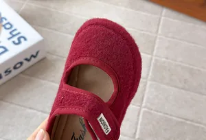 Dettaglio ravvicinato della trama in feltro bordeaux di una scarpa Mary Jane bimba.