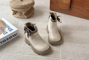 Close-up detail of beige girls boots featuring a plaid bow and durable rubber sole