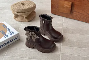 Close-up view of brown leather girls Martin boots featuring a houndstooth bow accent