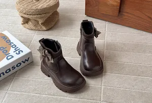 Detail of dark brown girls' leather boots featuring a houndstooth bow decoration.
