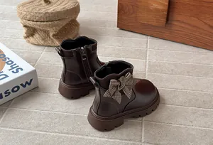 Close-up of brown children's boots with a decorative houndstooth bow in cozy indoor setting