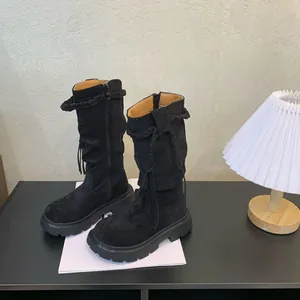 Detailed view of girls' black suede high boots with braided tassel accents.