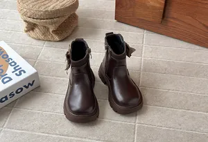 Close-up view of girls' brown winter boots with stylish houndstooth bow and side zipper