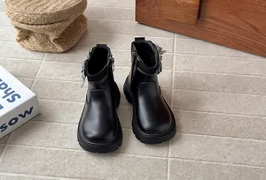 Close-up of girls black leather boots with houndstooth bow detail