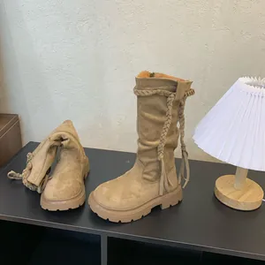 Close-up detail of beige suede girls' boots featuring braided tassels and thick sole