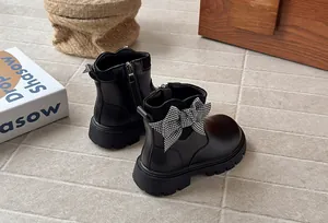 Detail view of black girl's boots featuring a stylish houndstooth bow decoration.