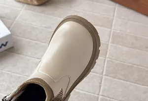 Close-up detail of beige French style girl's boots with houndstooth bow and knit collar