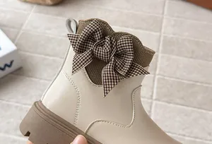 Close-up of the elegant houndstooth bow detail on cream-colored girl's ankle boots.