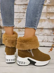 Detalle de botas de nieve de ante marrón con cuello de pelo sintético y suela blanca gruesa.