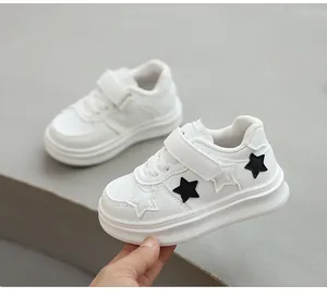 Close-up of white children's sneakers with black star patches and velcro straps