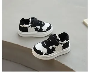 Detailed view of black and white children's sneakers featuring star patterns and velcro.