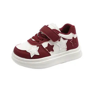 Detailed side view of children's white and burgundy sneakers with star patch design