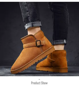 Detail view of brown suede snow boots with buckle worn by model in dark jeans.