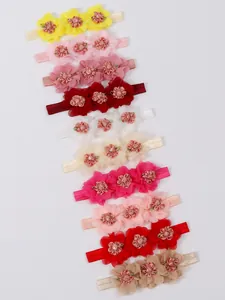 Detalle de diez diademas para bebé con flores de gasa de varios colores en blanco
