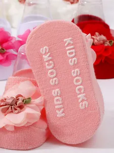 Primer plano de calcetines rosa para bebé con flor y suela antideslizante con letras