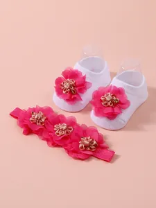 Detalle de calcetines blancos para bebé y diadema rosa con flores decorativas de malla