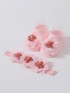 Primer plano de calcetines de bebé rosa y diadema con flores de malla fina