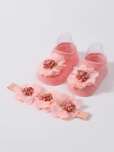 Vista detallada de calcetines rosas para bebé y conjunto de diadema floral a juego