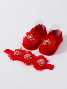 Vista detallada del conjunto de calcetines y diadema roja para bebé con flores
