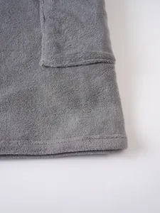 Macro detail showing the soft grey plush fabric texture and stitching of a bathrobe.