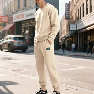 Vista lifestyle di un uomo che indossa un set di felpa e pantaloni beige in una strada al sole.