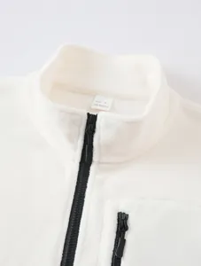 Close-up detail of a white fleece vest showing zipper and soft material texture