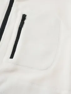 Detail shot of a white polar fleece vest showing the chest zipper pocket texture