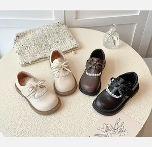 Selection of girls' bow leather shoes in cream, brown, and black colors on table