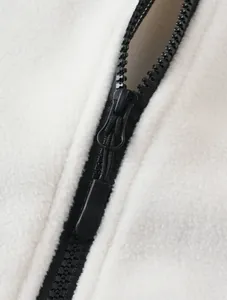 Macro detail showing the durable black zipper on white fuzzy fleece outdoor vest