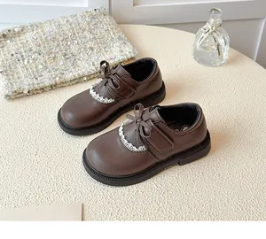 Detail view of girls' brown leather princess shoes with bow and lace trim