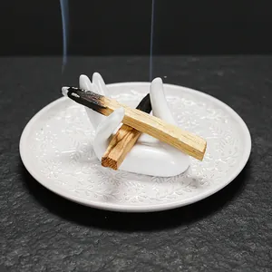 Witte keramische reliëf sieraden schaal met handhouder en brandende Palo Santo stokjes