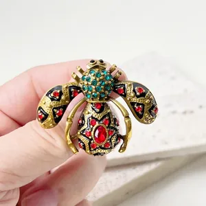 Detailed view of a vintage court-style bee brooch with enamel and sparkling rhinestones.