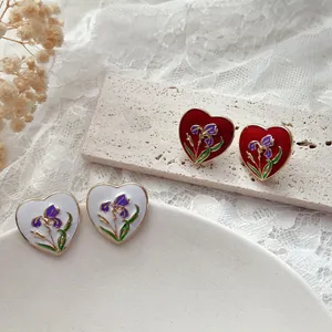 Primo piano di orecchini a cuore vintage con smalto a forma di iris viola.