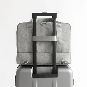 Large capacity grey travel duffel bag with integrated trolley sleeve shown on a silver suitcase handle