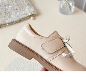 Detailed macro view of girls' cream leather princess shoe with bow and white lace trim.