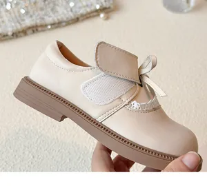 Detailed view of girls cream leather shoes with an elegant bow and lace trim design