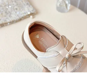 Close-up of girl's beige princess shoe with elegant bow and lace detail