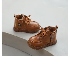 Pair of classic brown leather children's work boots displayed on a grey stone surface