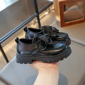 Detailed macro shot of black toddler girls' leather loafers with elegant bow decoration