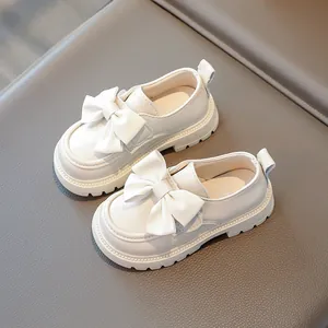 Close-up of white girls' princess loafers featuring a large decorative bow detail