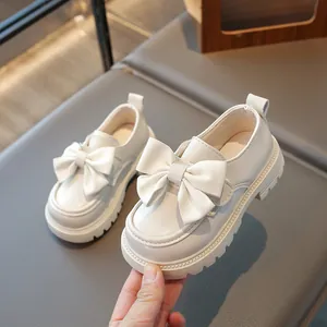 Detailed view of girls' creamy white princess loafers with large bow decoration