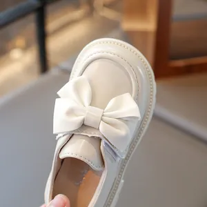 Detail shot of elegant beige girls' princess shoes featuring a large leather bow